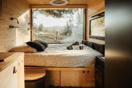 Saint-Julien-MolhesabateにあるRefuge panoramique en Haute-Loireの大きな窓が備わる小さな家の中のベッドルーム1室です。