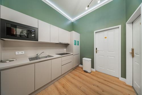 eine Küche mit weißen Schränken und einer weißen Tür in der Unterkunft HOME1 - District 5 Boutique Hostel in Wien