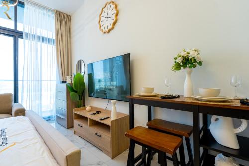 a living room with a table and a tv and a couch at Bright Studio with Balcony the Gate, Masdar City in Abu Dhabi