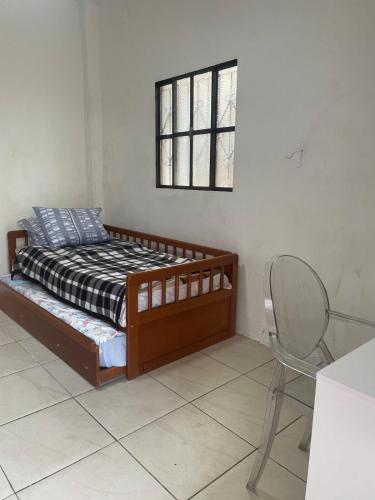 a bedroom with a bed and a chair and a window at JK térreo Zona Norte in Porto Alegre