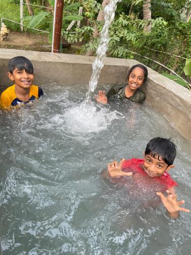 two children swimming in a fountain with a woman at Srirangam Heritage Farmhouse - Perfect Spot for Parties & Events in Tiruchchirāppalli