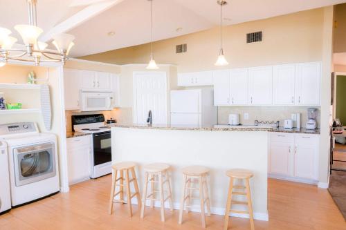 a kitchen with white cabinets and bar stools at Lozano Lake House in Buncome