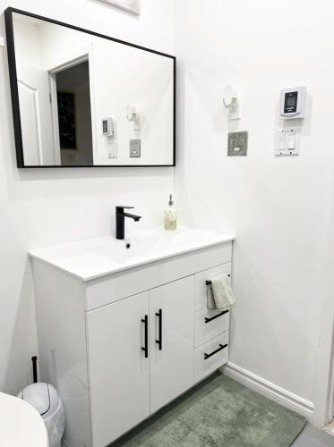 a white bathroom with a sink and a mirror at Top Rated Vacation House Montreal Private Parking in Laval