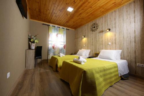 Habitación de hotel con 2 camas con sábanas amarillas en Happy House, en Faro
