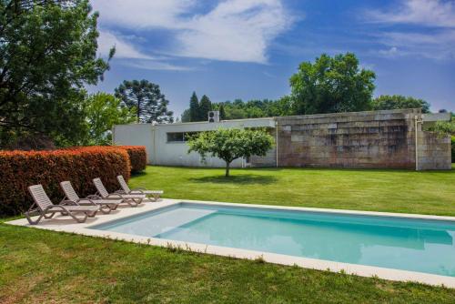 a swimming pool in a yard with chairs and a house at The Luxury and Nature Retreat with pool, jacuzzi & BBQ in Vila Fonche