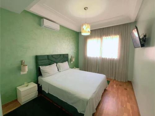 Un dormitorio con una cama blanca y una pared verde. en Ibiz Appartement, en Casablanca