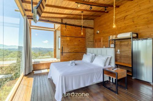 une chambre avec un lit blanc et une grande fenêtre dans l'établissement Cabana de luxo na Serra Catarinense VST018, à São Paulo dos Pinhais