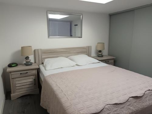 a bedroom with a bed with a mirror and two lamps at Villa Pinede du Golf PORT LEUCATE in Port Leucate