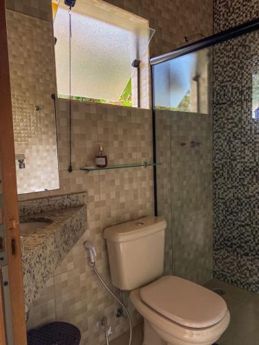 a bathroom with a toilet and a glass shower at Pousada Vale do Horizonte in Monte Verde