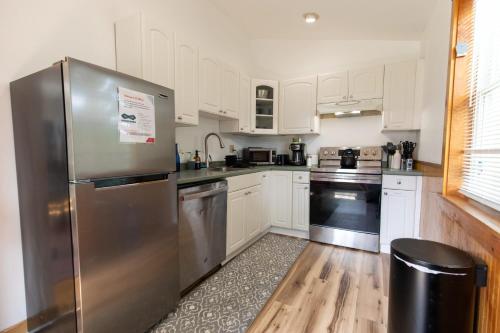 eine Küche mit weißen Schränken und einem Edelstahlkühlschrank in der Unterkunft Entire 1 Bdrm house 5 mins from NWMC and DwnTwn in Saint Albans