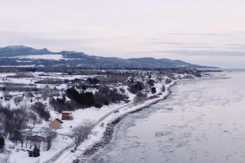 een uitzicht op een rivier met sneeuw op de grond bij Condo Bord de fleuve Piscine - Les Voitures d'Eau in L'Isle-aux-Coudres