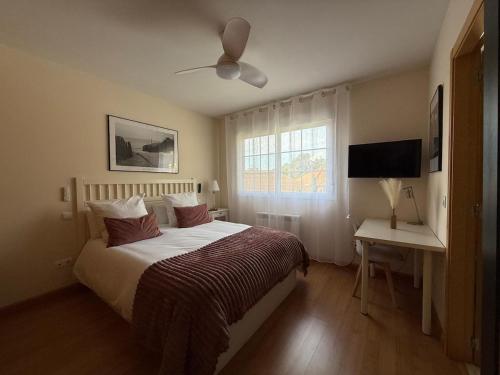 a bedroom with a bed and a desk and a window at Acogedor chalet con jardín ideal para desconectar in Sotillo de la Adrada