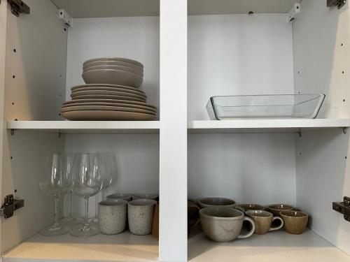 two shelves with dishes and wine glasses in a kitchen at Lovely 1BR & 1LR Apartment, Only 15 Min Walk to City Center in Ghent