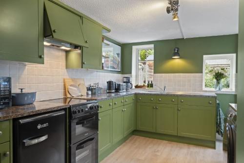 a kitchen with green cabinets and a black dishwasher at Cottage in central Porlock with garden & parking in Porlock