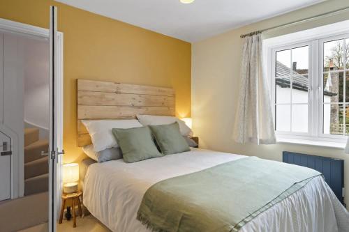 a bedroom with a large bed and a window at Cottage in central Porlock with garden & parking in Porlock