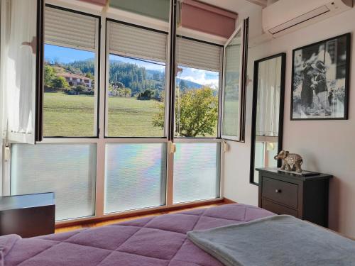 une chambre avec de grandes fenêtres et un lit avec des draps violets dans l'établissement APARTAMENTO VALMAYOR, à Potes