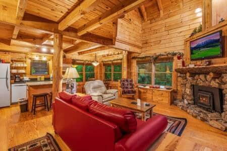 a living room with a red couch and a fireplace at In the Pines. Great location. Privacy in Hornet
