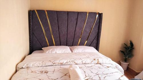 a bed with a black headboard in a bedroom at Deluxe Homes, Voi in Voi
