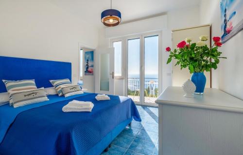 a bedroom with a blue bed and a vase with flowers at La Casa sul Golfo - the House on the Gulf in Massa Lubrense