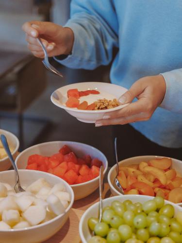 una persona que sostiene un tazón de comida junto a tazones de fruta en Hotel AM MEER & Spa, en Binz