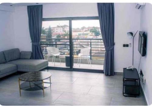 Una sala de estar con un sofá y una mesa y un balcón. en Amal Suites, en Accra