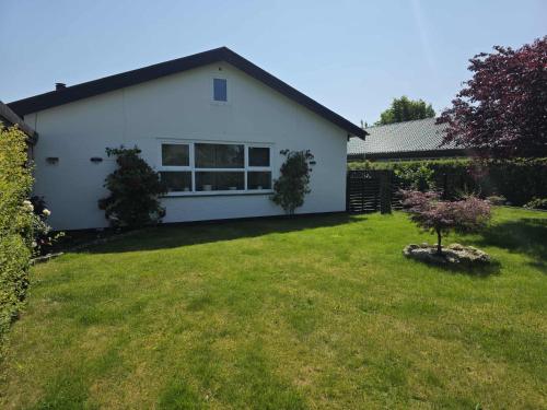 a white house with a yard with a tree at Guesthouse Near Nature & Shops in Kolding
