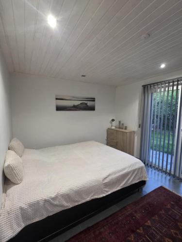 a bedroom with a white bed and a large window at Guesthouse Near Nature & Shops in Kolding