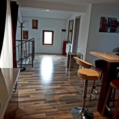 a living room with a wooden floor and bar stools at Mansarda lu' Ion in Tîrgu Neamţ