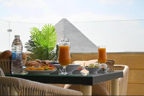 uma mesa com comida e bebidas e as pirâmides em AKEN Pyramids View em Cairo