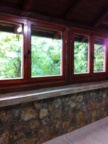 a room with three windows and a stone wall at Apartment Vistanova in Vrdnik