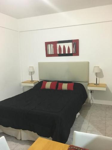 um quarto com uma cama preta com 2 mesas e 2 candeeiros em Apartamento Los Abuelos em Colón
