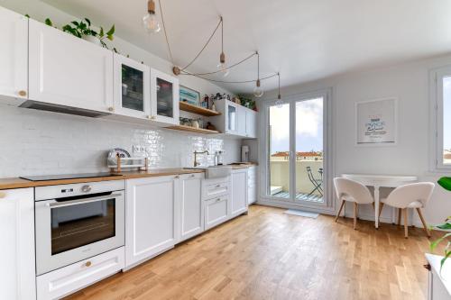 a kitchen with white cabinets and a table with chairs at Appartement Le perchoir - Welkeys in La Guillotière