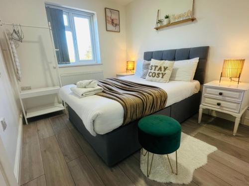 a bedroom with a large bed with a green stool at Modern & Cosy 2-Bed Apartment Near NEC, Airport & JLR! in Birmingham