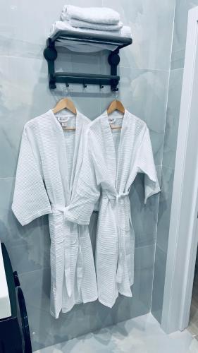 two white shirts on a rack in a closet at Новая Евродвушка&Комфорт КЖБИ in Kostanay