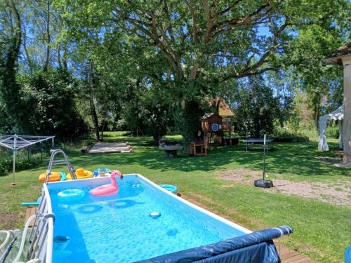- une piscine dans une cour avec un arbre dans l'établissement Le PRESSOIR, à Ouville-la-Bien-Tournée