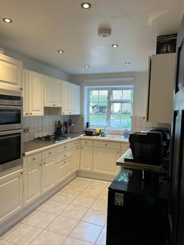 a kitchen with white cabinets and a black refrigerator at Room with private bathroom 5 min to Legoland & Windsor Castle - free parking and EV plug in Windsor