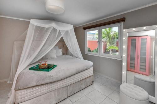 ノールトにあるBeach house with pool in noordのベッドルーム(天蓋付きベッド1台、窓付)