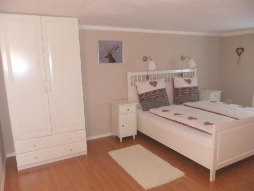 a bedroom with a white bed and a white cabinet at Allgäu Apartment in Memmingen