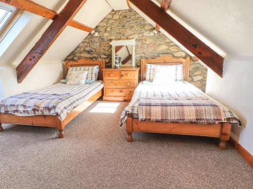 a attic bedroom with two beds and a stone wall at Ty Gwartheg in Dinas