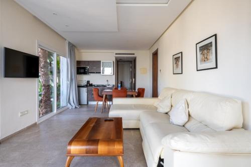 een woonkamer met een witte bank en een tafel bij Le Tanger Résidence Hôtelière in Tanger