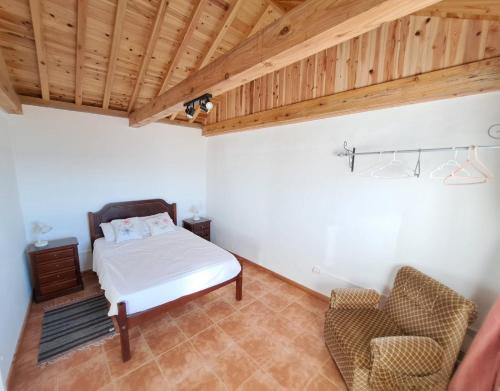 a bedroom with a bed and a chair at Baía do Porto das Lajes in Lajes das Flores