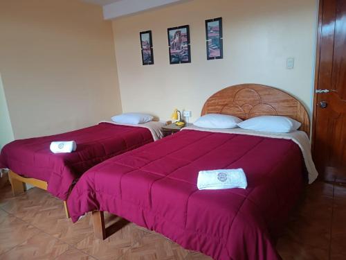 two beds in a room with pink sheets at Marlon's INN Cusco II in San Antonio