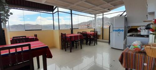 a room with tables and chairs and a kitchen with windows at Marlon's INN Cusco II in San Antonio