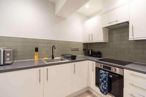 a kitchen with white cabinets and a sink at Modern 1 Bedroom Apartment in Brockley, SE London in London