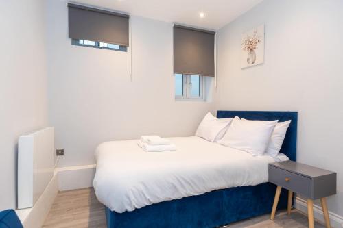 a bedroom with a large bed with a blue headboard at Modern 1 Bedroom Apartment in Brockley, SE London in London