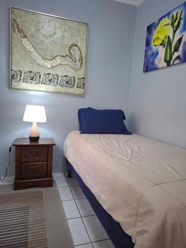 une chambre avec un lit et une table avec une lampe dans l'établissement Tropical Palm Retreat, à Willemstad