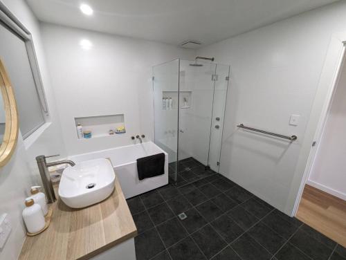 a white bathroom with a sink and a shower at Sails in the heart town walk to beach and coffee in Kingscote