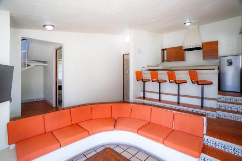 an orange room with orange chairs and a kitchen at Villas del Sol Hotel & Bungalows in Oaxaca City