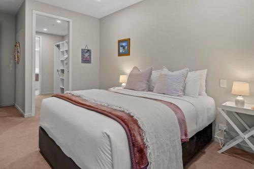 a bedroom with a large white bed with pillows at Premium Coastal Abode with Parking Near Beach in Okura