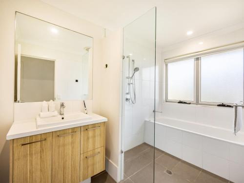 een witte badkamer met een wastafel en een douche bij Elegant 5BR Family Home Modern Comfort in Rochedale in Rochedale